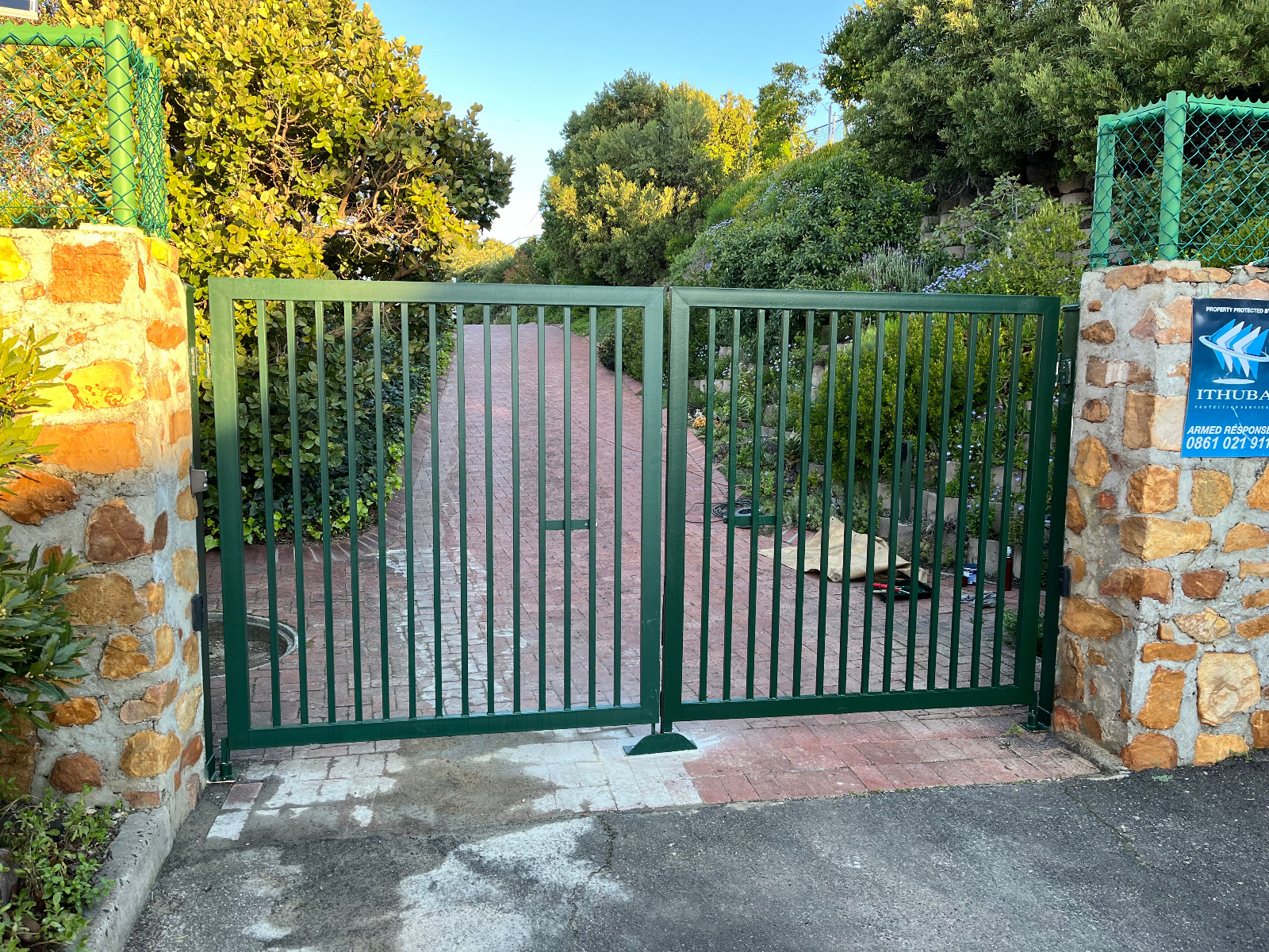 Green steel swing driveway gate with vertical bars installed in Melkbosstrand